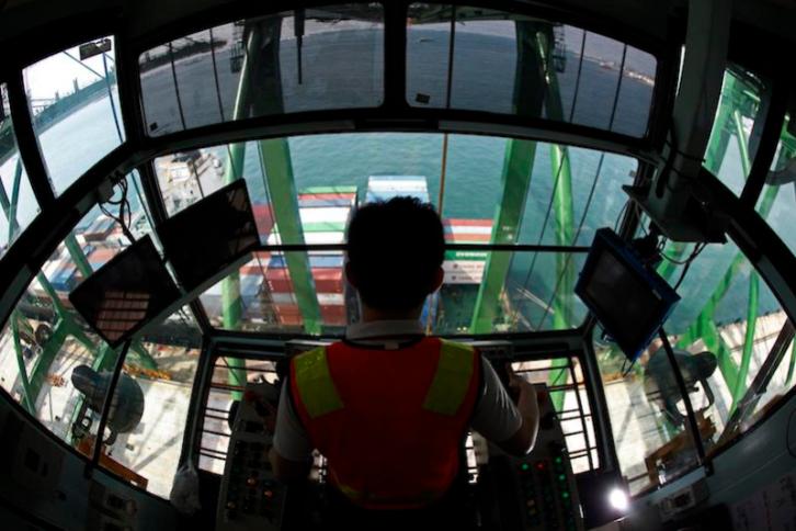 A crane operator unloads containers from a ship at a PSA International port terminal in Singapore